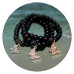 Armband met gladde zwarte kralen en goudkleurig vlindertje