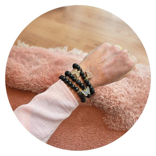 Armband met gladde zwarte kralen en goudkleurig vlindertje