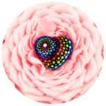 houten hartje met dot painting op een achtergrond van roze bloemblaadjes.