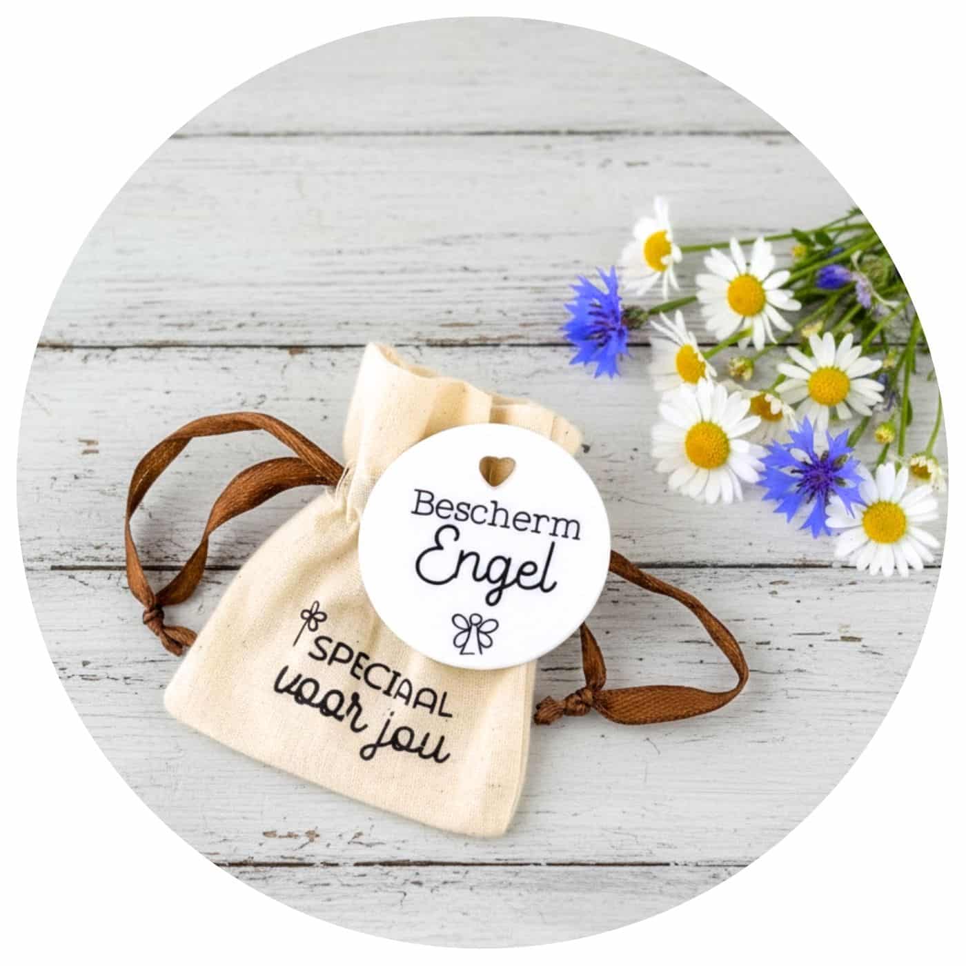 Pocket-Hug-beschermengel-bloemen Bescherm Engel pocket hug liggend op een draagtasje met enkele wilde bloemen vlakbij