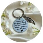 sleutelhanger met engelvleugel omringd door witte bloemen